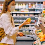 Grocery Shopping - Woman in Yellow Tshirt and Beige jacket Holding a Fruit Stand