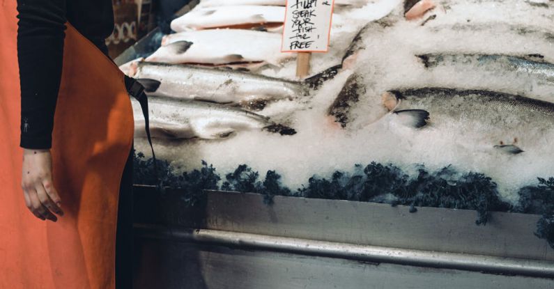 Stock Markets - A woman in an apron standing in front of a fish market