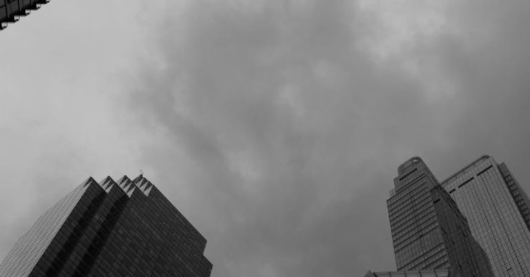 Financial Literacy - Black and white photo of tall buildings with cloudy sky